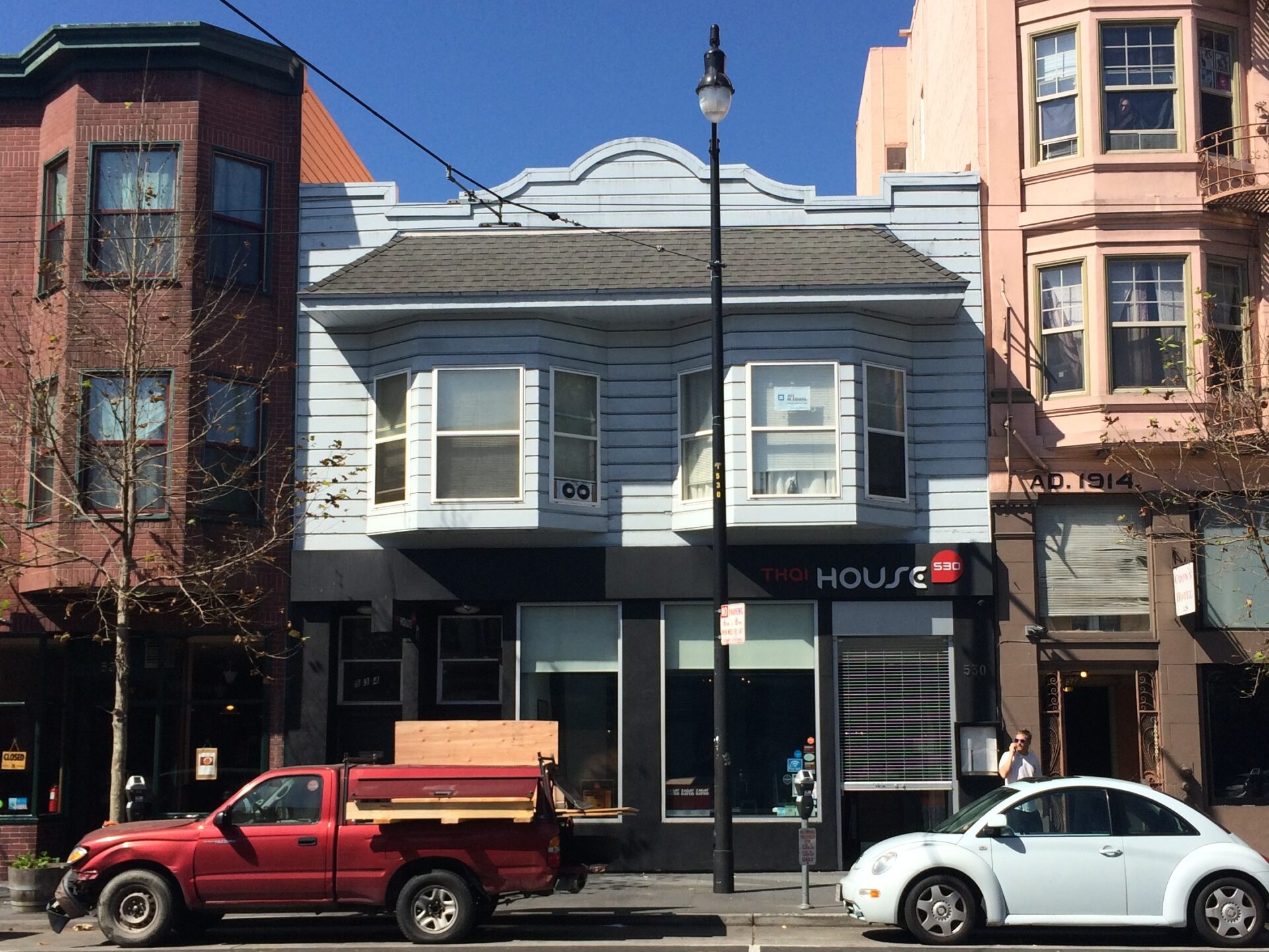 A modern daytime photo of a two-story building with bay windows and a gray facade, with a business called &ldquo;HOUSE&rdquo; on the ground floor.